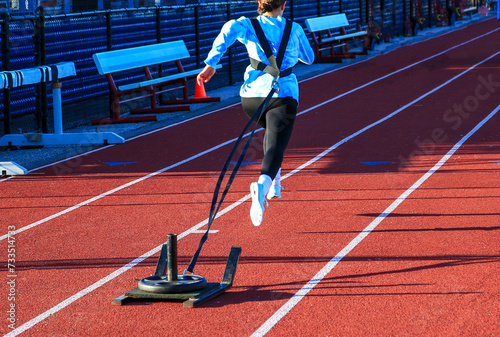 Girl running pulling a sled with weight on a track