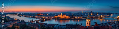 Historic city panorama at twilight, with illuminated landmarks against a deep blue sky