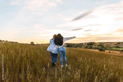 back view of two female friends hugging in a field
