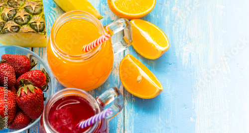 Fresh pineapple and strawberry smoothie in glasses with fruits on a blue wooden rustic background