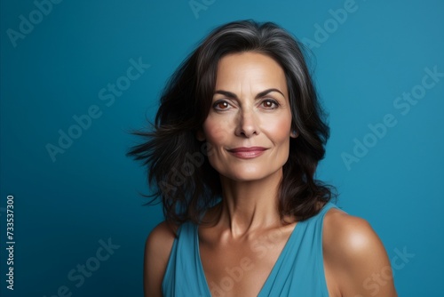 Portrait of beautiful mature woman in blue dress on blue background. photo