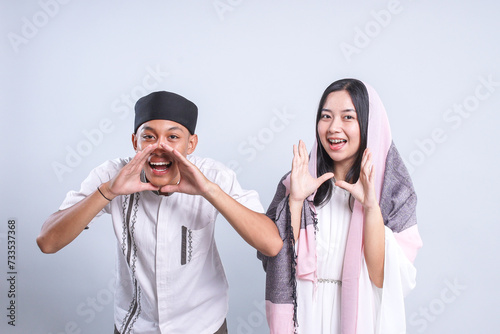 Young Asian muslim male and female putting their hands near mouth while yelling