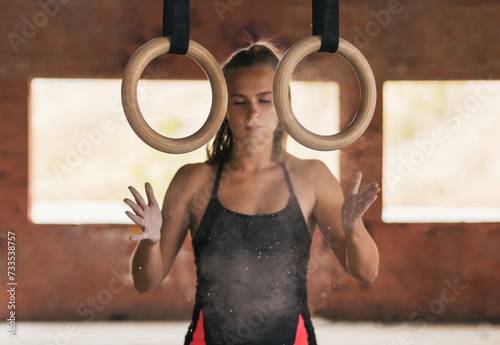 female athlete clapping with chalk in her hands. getting ready to train with gymnastic rings photo