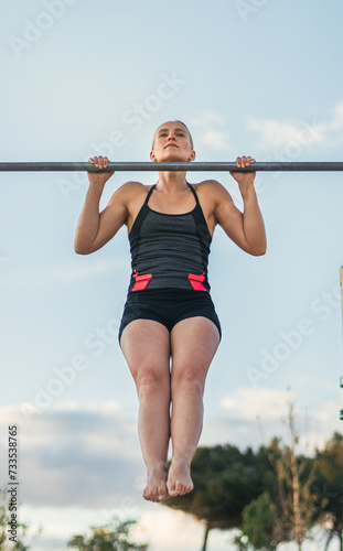 woman athlete doing pull ups on a bar outdoors. calisthenics