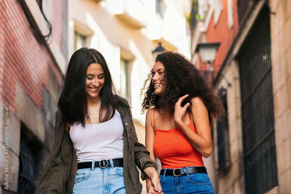 two young women going down street stairs smiling holding her hands two young women going down street stairs smiling holding her hands