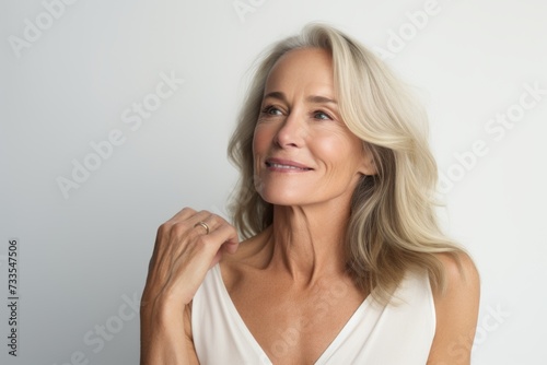 Portrait of a beautiful mature woman with long blond hair, looking away and smiling.