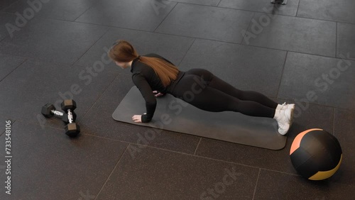 Young caucasian fitness woman doing push ups during training in fitness studio. Top view. Active lifestyle concept. photo
