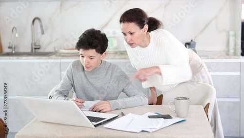 Boy studiyng using laptop, mother helping and explaining. Boy studiyng, mother helping. High quality 4k footage photo