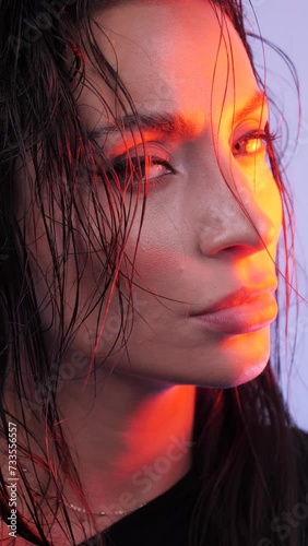 close-up of a girl with wet hair, turns her head and looks at the camera, in red light on the floor of her face