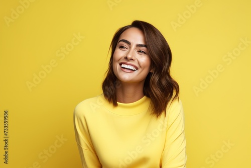 happy smiling young woman in yellow sweater over yellow background  empty space