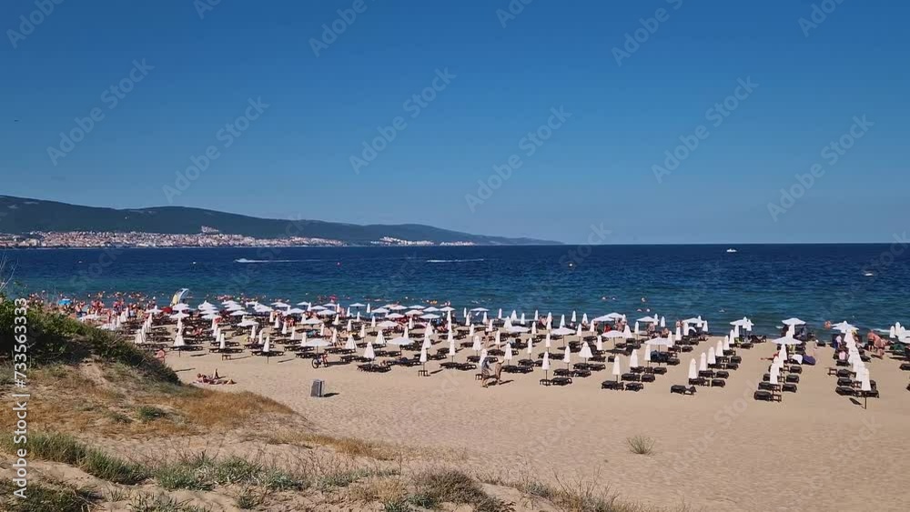 Sunny Beach resort scene with sunbeds on the sand in front of the blue sea, Burgas, Bulgaria. Summer vacation, holiday relaxation concept Sunny Beach resort scene with sunbeds on the sand in front of the blue sea, Burgas, Bulgaria. Summer vacation, holiday relaxation concept