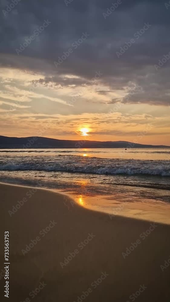 Calm morning seaside with beautiful sunrise at horizon and foamy waves hits the sandy beach Calm morning seaside with beautiful sunrise at horizon and foamy waves hits the sandy beach