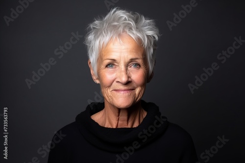 Portrait of a happy senior woman with grey hair on black background