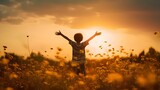 A little boy raises his hands above the sunset sky, enjoying life and nature. Happy kid on a summer field looking at the sun. Silhouette of a male child in the sun. Fresh air, environment concept.
