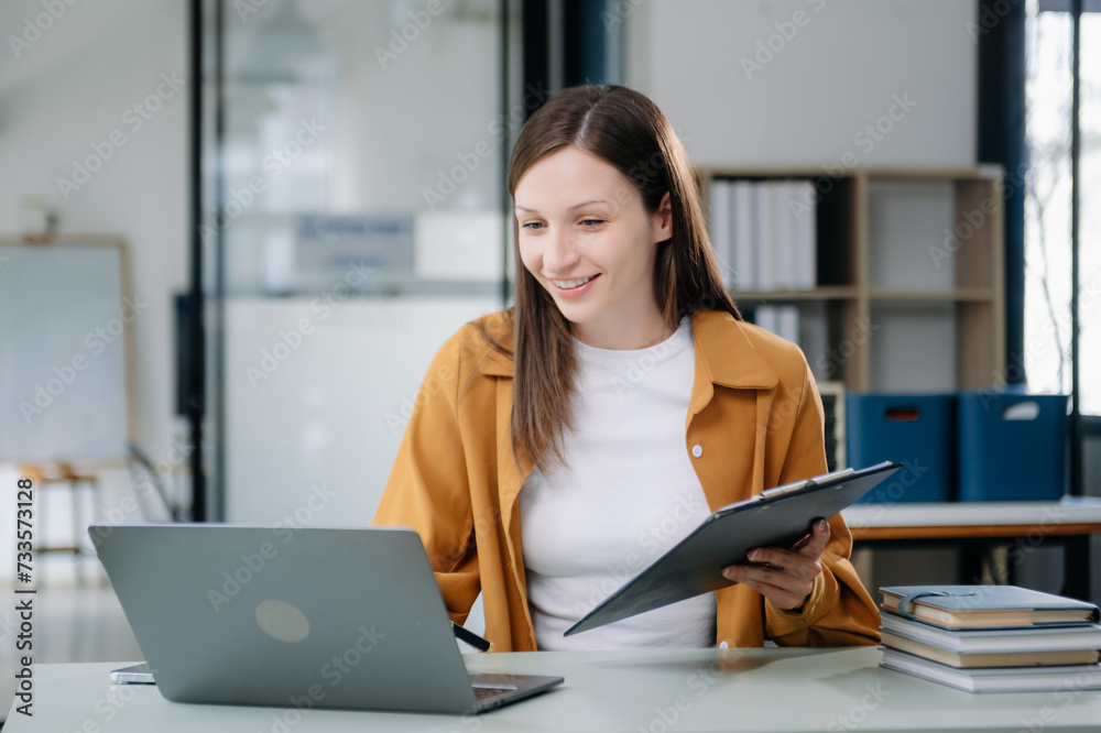 Confident woman with a smile standing holding notepad and tablet at the office. Confident woman with a smile standing holding notepad and tablet at the office.