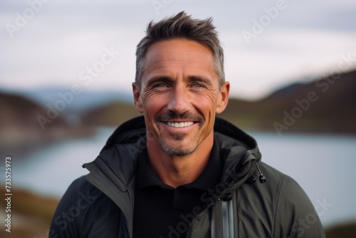Portrait of a handsome middle-aged man smiling at camera outdoors.