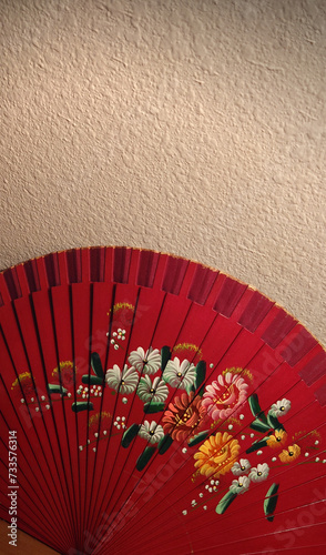 hand painted red traditional Asian fan against a textured wall backdrop 