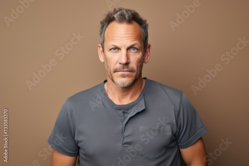 Handsome middle-aged man in a gray t-shirt on a brown background © Iigo