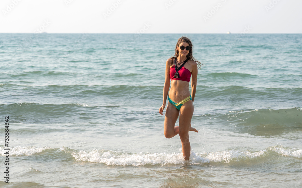 Portrait of smiling fashion woman relaxation on the tropical beach.Happy young beautiful girl enjoying and having fun on the tropical island.Summer vacation and travel