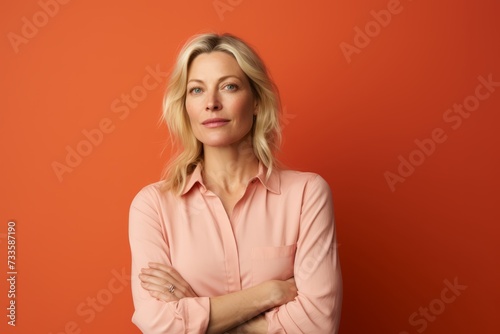 Portrait of a beautiful middle-aged woman in a pink shirt on a orange background