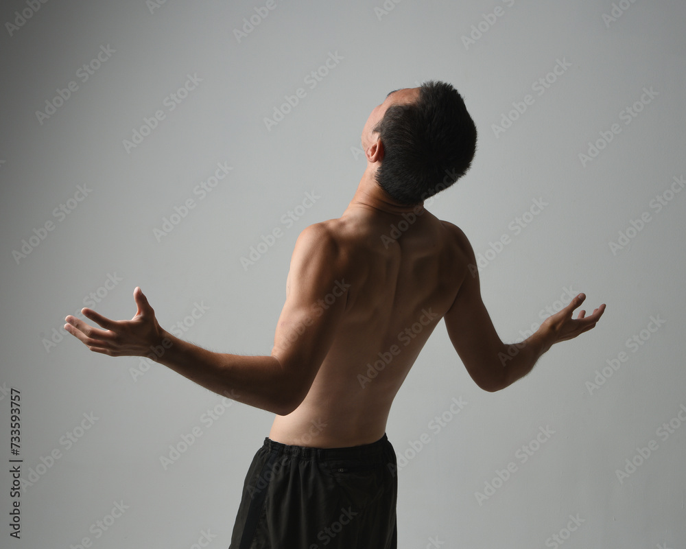 Close up portrait of fit asian male model, shirtless with muscles.  gestural ti chi inspired posing with arms reaching out. Isolated on a white studio background with moody silhouette.