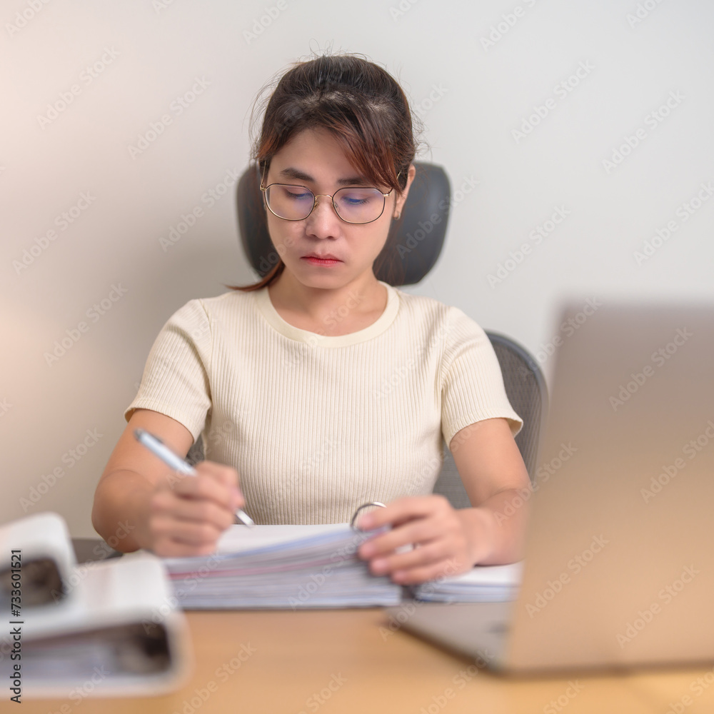 Asian woman working with computer laptop, female businesswoman reading report and sign contract with documents folder stack at home or office late night. Overworked, work hard and business concept Asian woman working with computer laptop, female businesswoman reading report and sign contract with documents folder stack at home or office late night. Overworked, work hard and business concept