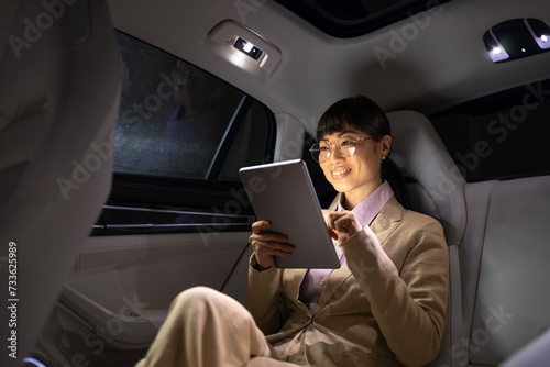 Female Asian business person traveling in luxurious limousine and having important video call.