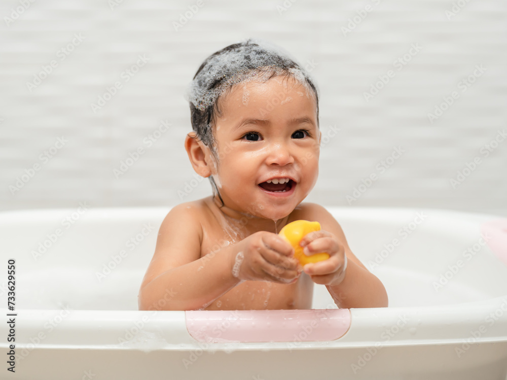 happy infant baby take a bath and playing rubber duck with foam bubbles in bathtub happy infant baby take a bath and playing rubber duck with foam bubbles in bathtub