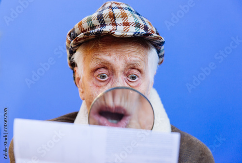Funny portraits with old grandmother. Senior woman acting as an investigator with the magnifying lense