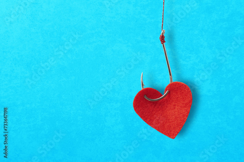 The heart and the fishing hook on blue background with copy space