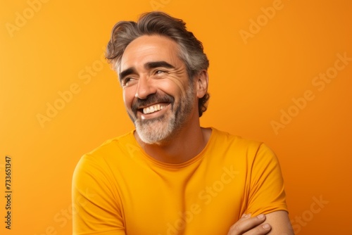 Portrait of handsome middle-aged man in yellow t-shirt on orange background