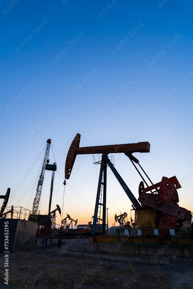In the evening, oil pumps are running, Silhouette of beam pumping unit In the evening, oil pumps are running, Silhouette of beam pumping unit
