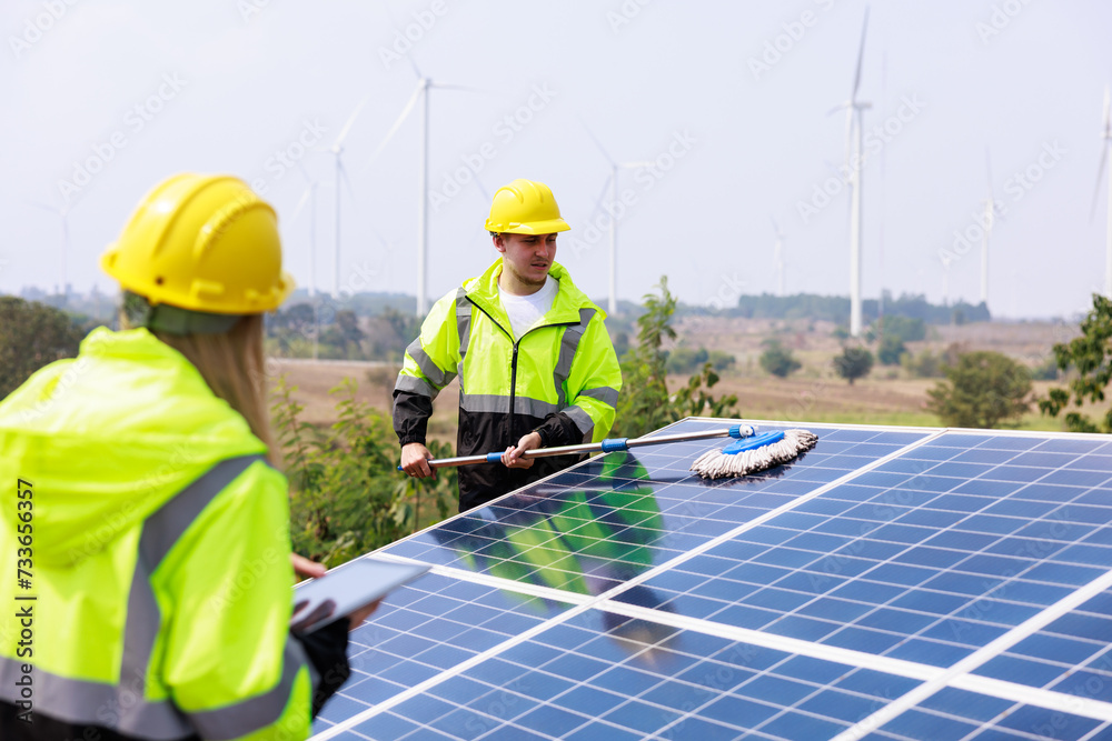 engineers examining solar panel using digital taplet computer in solar farm. solar panel cleaning officer background.