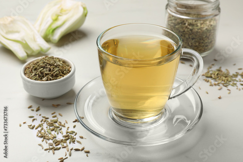 Aromatic fennel tea, seeds and fresh vegetable on white table, closeup