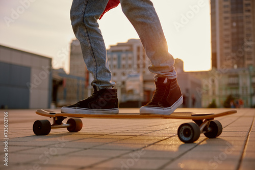 Legs of hipster man riding skateboard in skatepark, closeup photo