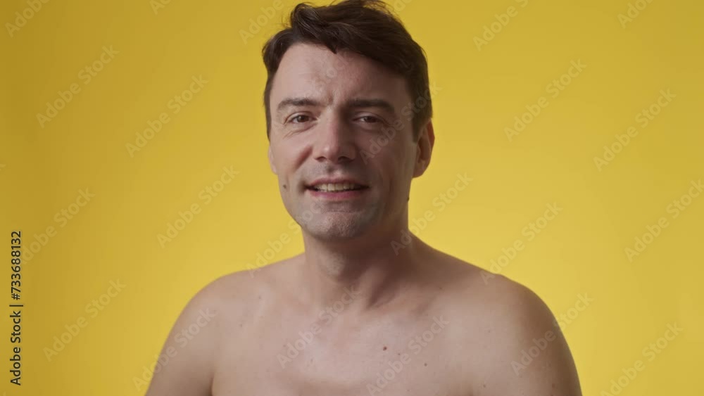 Studio shot of smiling middle-aged Caucasian man looking at camera in yellow background, copy space Studio shot of smiling middle-aged Caucasian man looking at camera in yellow background, copy space