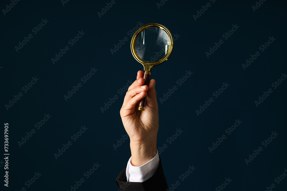 A businessman's hand holds a magnifying glass A businessman's hand holds a magnifying glass
