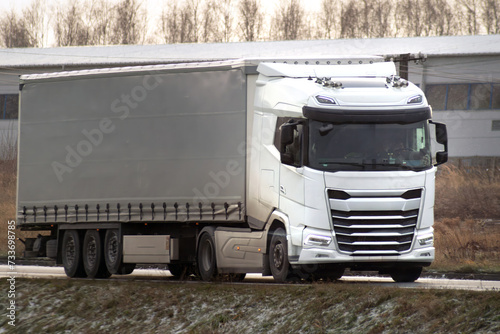 The snowy highway is a challenge for the transport truck. The semi-trailer delivers cargo to the shipping industry. photo