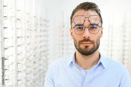Man is choosing glasses in optics store