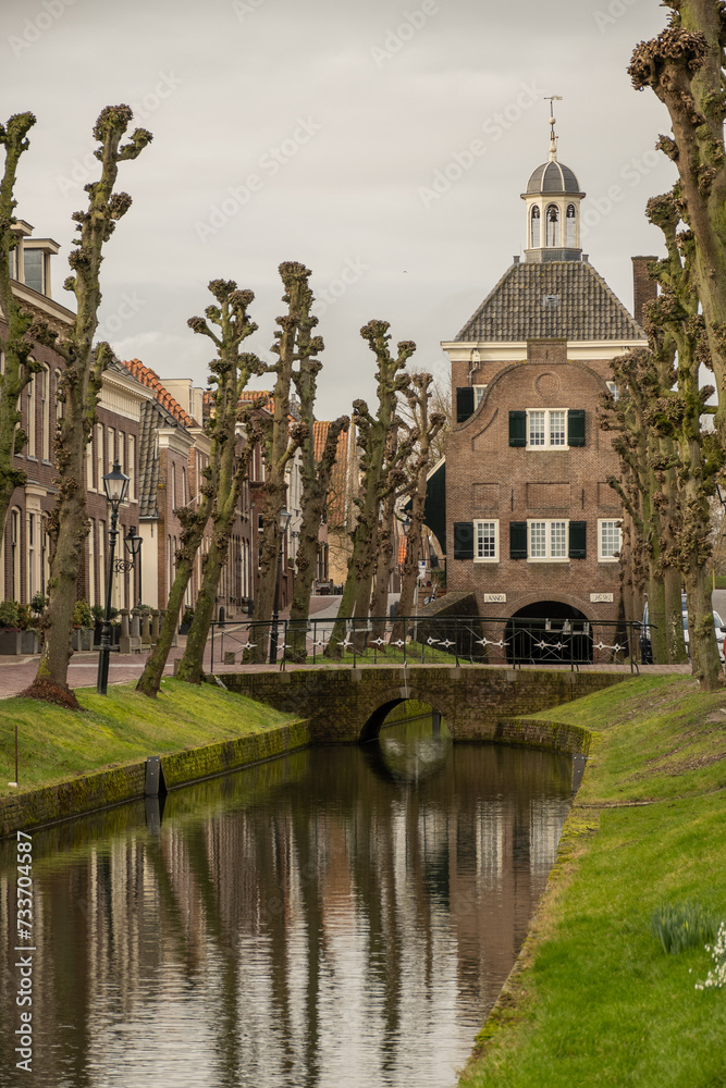 binnenhaven road leading to town hall Stadhuis van Nieuwpoort in historic fortified town on Old Dutch Waterline on cloudy stormy day. old building and bridge reflection in city canal