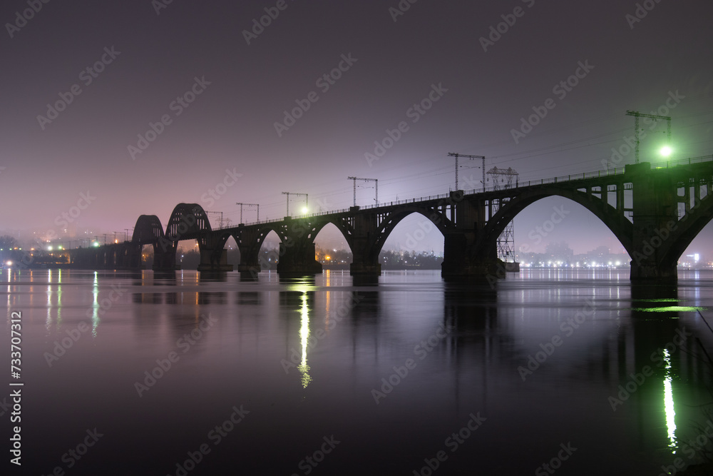 Fototapeta premium Scenic view of the city of Dnepr in the winter evening. Dnipro in the evening. Ukrainian city in winter at night. background image. Panoramic view. Long exposure photo of the Dnieper River at night.