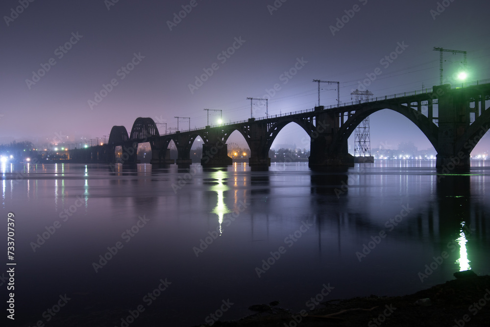 Fototapeta premium Scenic view of the city of Dnepr in the winter evening. Dnipro in the evening. Ukrainian city in winter at night. background image. Panoramic view. Long exposure photo of the Dnieper River at night.