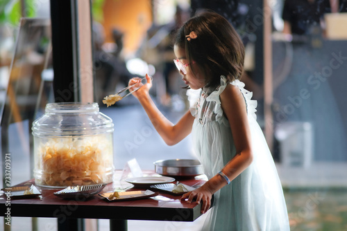A little girl is taking some crackers from a glass container photo