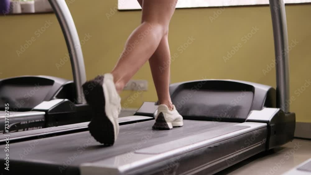 View of the sneakers of an athletic young girl walking on a treadmill in the gym. Super slow motion. View of the sneakers of an athletic young girl walking on a treadmill in the gym. Super slow motion.