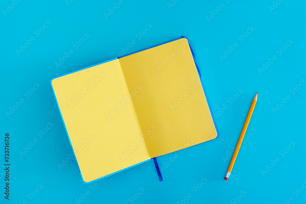 Open yellow notepad on a blue background, top view. Open yellow notepad on a blue background, top view.