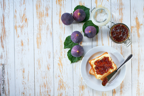 Toasts of bread with figs jam and fresh fruits  on white wooden table. Top view.