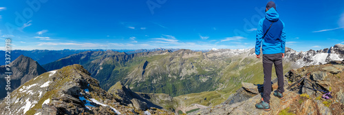 Hiker man with scenic view of majestic mountain peaks of High Tauern seen from Feldseekopf, Carinthia Salzburg, Austria. Idyllic hiking trail in Goldberg group in wild remote Austrian Alps. Wanderlust