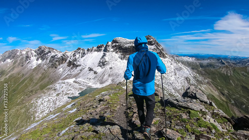 Hiker man with scenic view of majestic mountain peaks of High Tauern seen from Feldseekopf, Carinthia Salzburg, Austria. Idyllic hiking trail in Goldberg group in wild remote Austrian Alps. Wanderlust