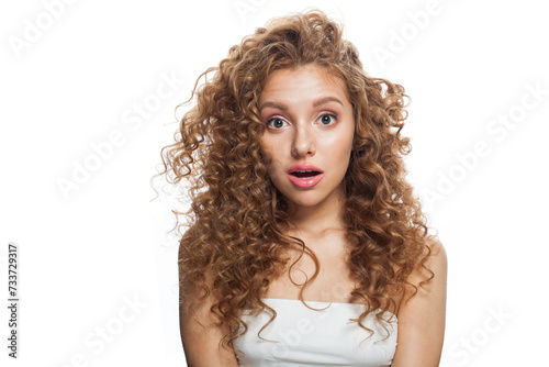 Surprise woman looking up with opened mouth. Healthy excited female model with natural make-up, shiny clear skin and long curly hairstyle isolated. Haircare, Skincare, Cosmetology and Styling concept