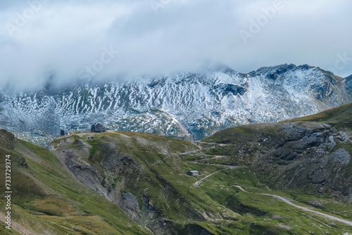 Scenic view of mountain hut Hagenerhuette surrounded by cloud covered mountain peaks of High Tauern, Carinthia Salzburg, Austria. Idyllic hiking trail in Goldberg group in wilderness of Austrian Alps photo